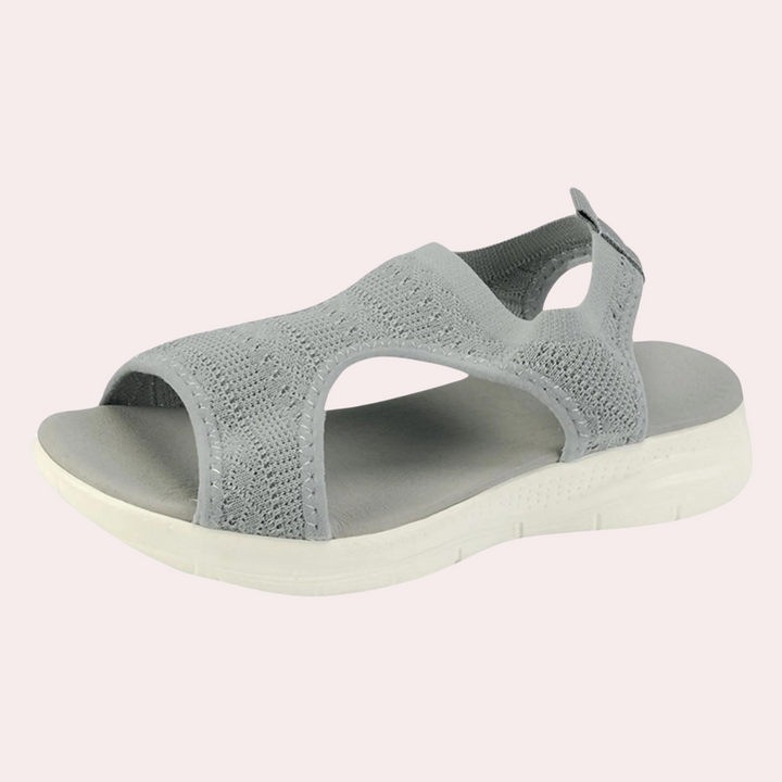 Grijze dames sandaal met open teen, elastisch gebreid bovenwerk en witte zool. Comfortabele zomerschoen, ideaal voor casual en dagelijks gebruik.