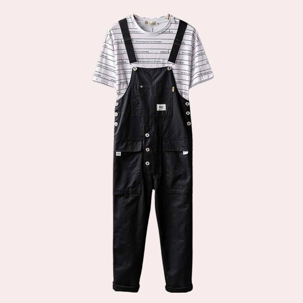 Zwarte denim overall met knopen en zakken, gedragen over een gestreept T-shirt. Modieuze unisex kleding, casual stijl, comfortabele pasvorm.