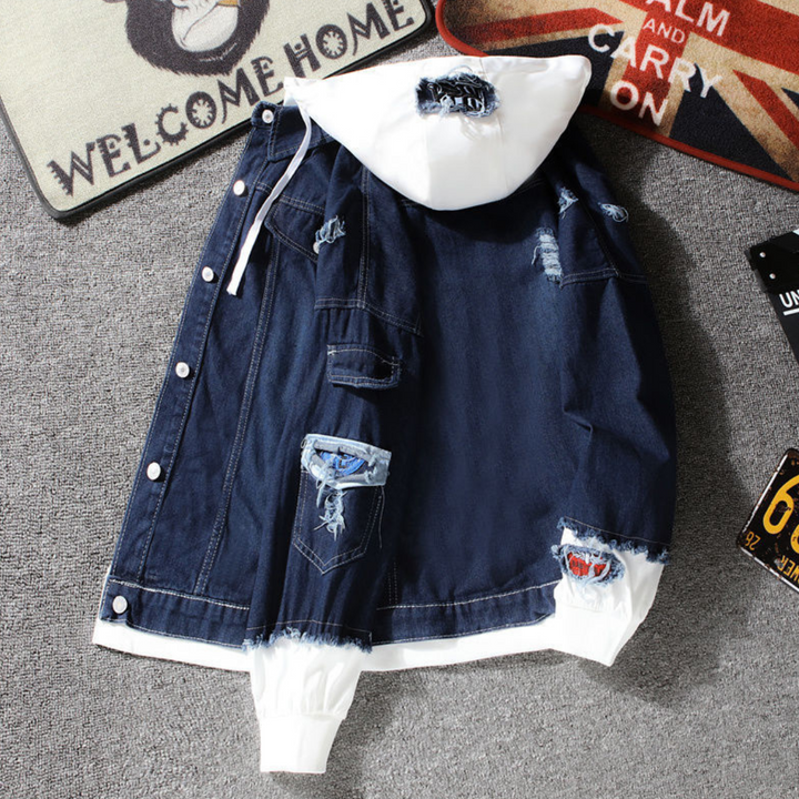 Donkerblauwe spijkerjas met witte capuchon, versierd met patches en scheuren, op grijze vloer met decoratieve matten. Modieuze streetwear stijl.