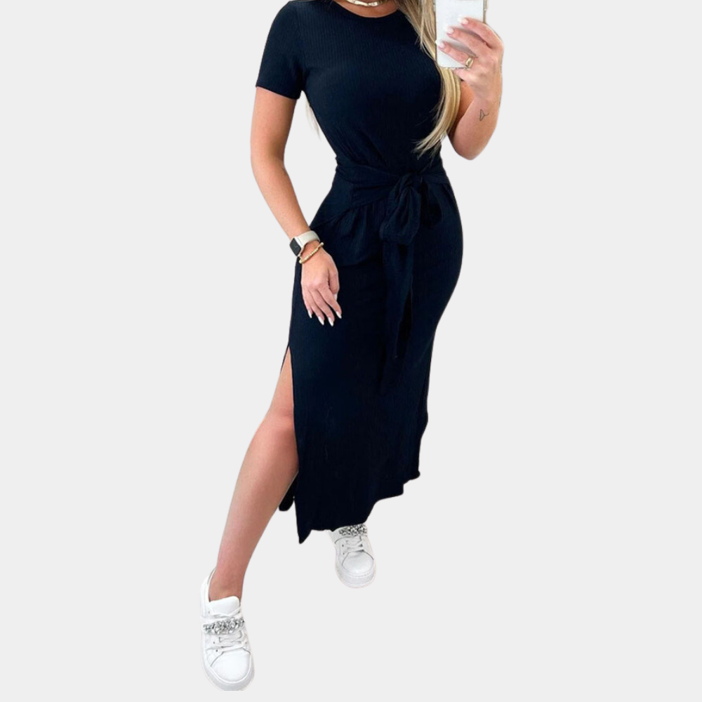 Vrouw in zwarte midi-jurk met korte mouwen en strik, gecombineerd met witte sneakers. Modieuze dameskleding, casual chique stijl.