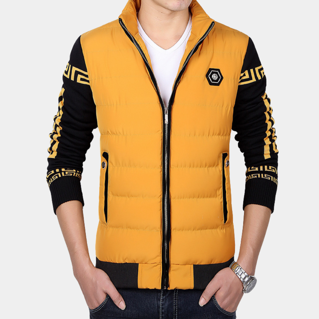 Man in gele gewatteerde jas met zwarte mouwen en geometrisch patroon, rits en zakken. Modieuze herenkleding, casual stijl.
