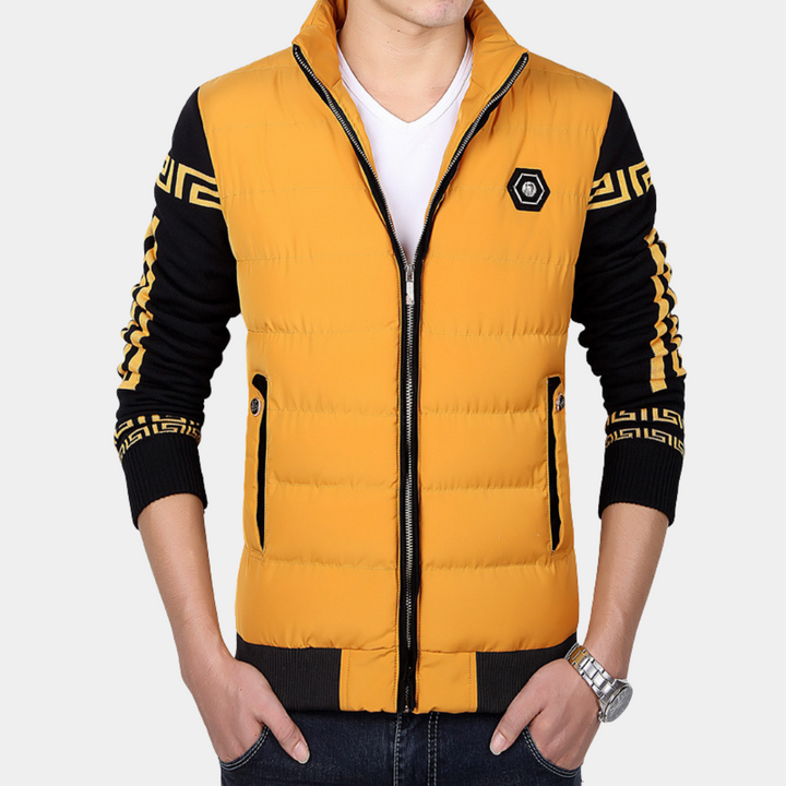 Man in gele gewatteerde jas met zwarte mouwen en geometrisch patroon, rits en zakken. Modieuze herenkleding, casual stijl.