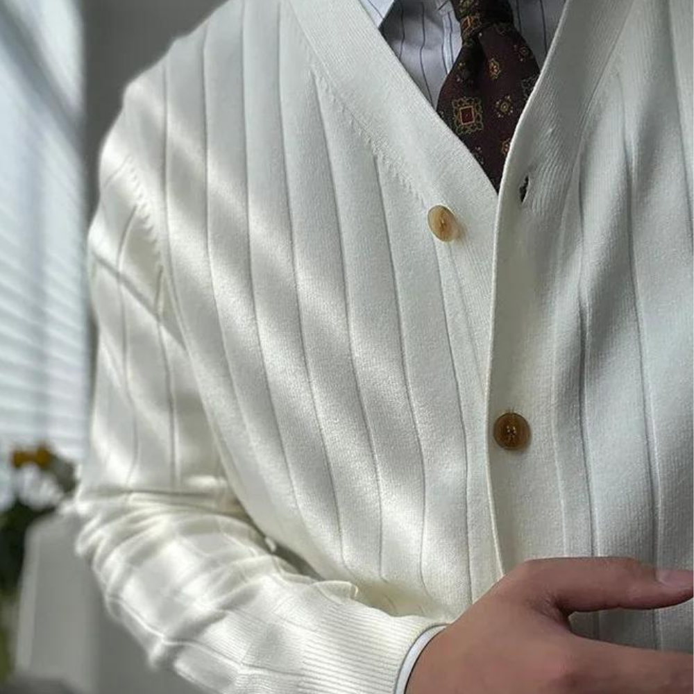 Witte geribbelde cardigan met bruine knopen, gedragen over een gestreept overhemd en stropdas. Stijlvolle herenkleding, elegante mode.
