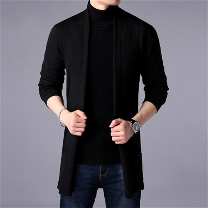Man in zwarte coltrui en open vest, casual herenkleding, modeaccessoire, horloge, grijze achtergrond. Stijlvolle outfit voor moderne mannen.