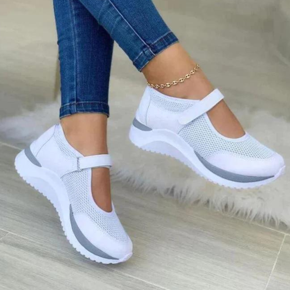 Witte dames sneakers met klittenband, ademend mesh, comfortabele zool, gedragen met blauwe jeans. Perfect voor casual en sportieve outfits.