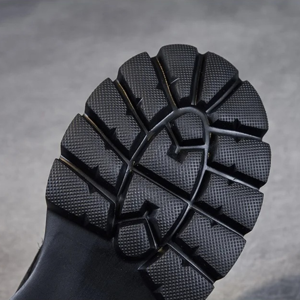 Zwarte rubberen zool van een laars met diep profiel, antislip ontwerp, ideaal voor outdoor activiteiten en werk, duurzame grip en slijtvast.