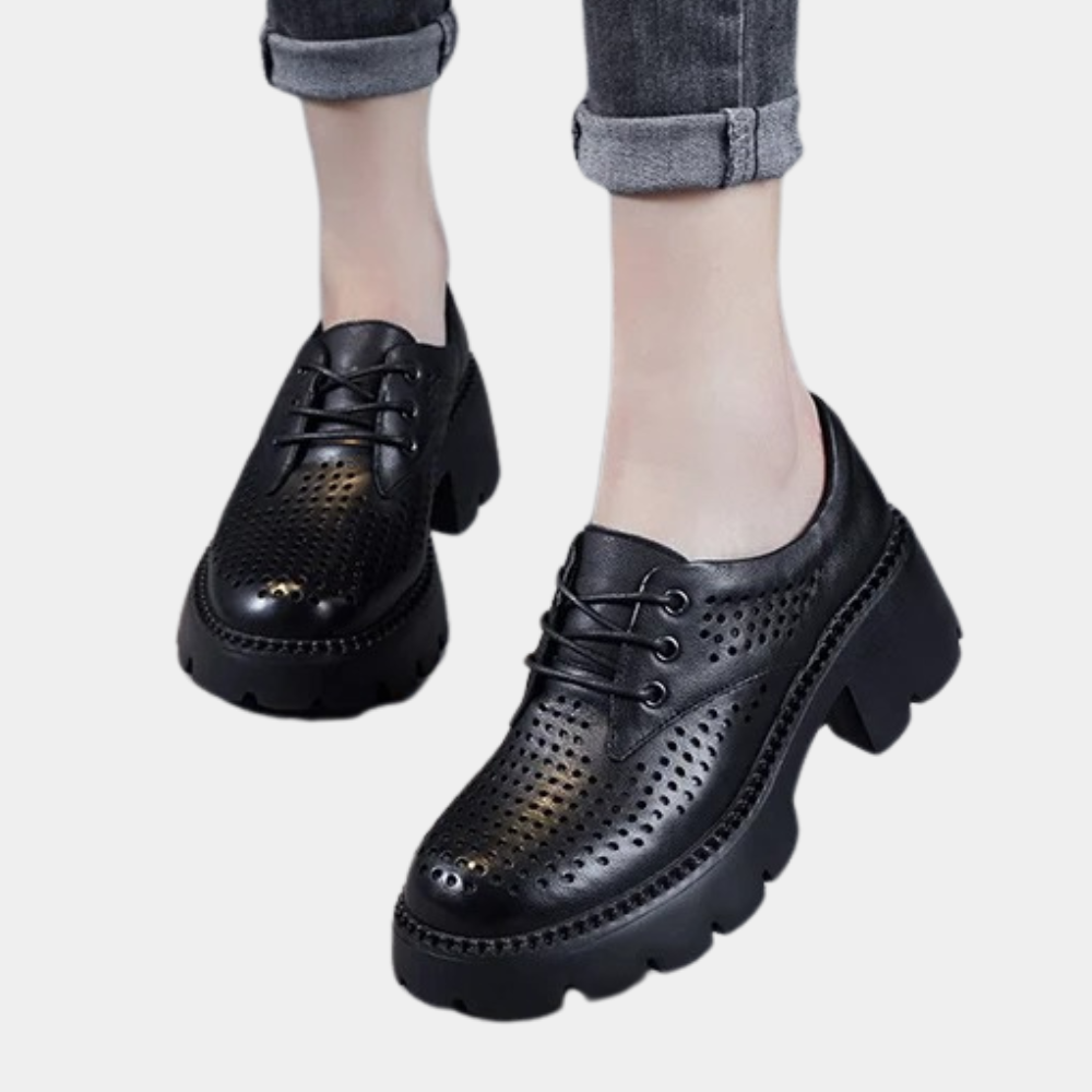 Zwarte leren damesschoenen met dikke zool en perforaties, vetersluiting. Modieuze, comfortabele schoenen voor dagelijks gebruik.