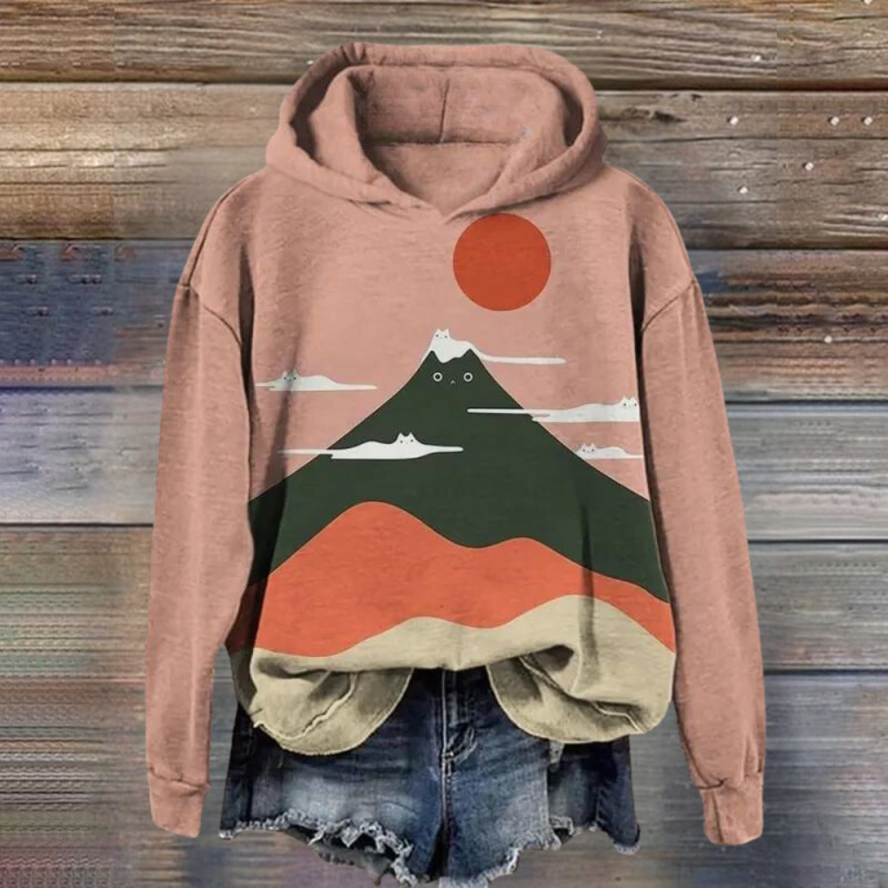 Roze hoodie met bergprint, zon en wolken, gecombineerd met denim shorts. Trendy dameskleding, casual streetwear, comfortabele mode.