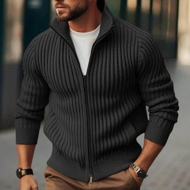 Zwarte gebreide herenvest met ritssluiting, gedragen over een wit T-shirt. Stijlvolle casual herenkleding, perfect voor herfstmode.