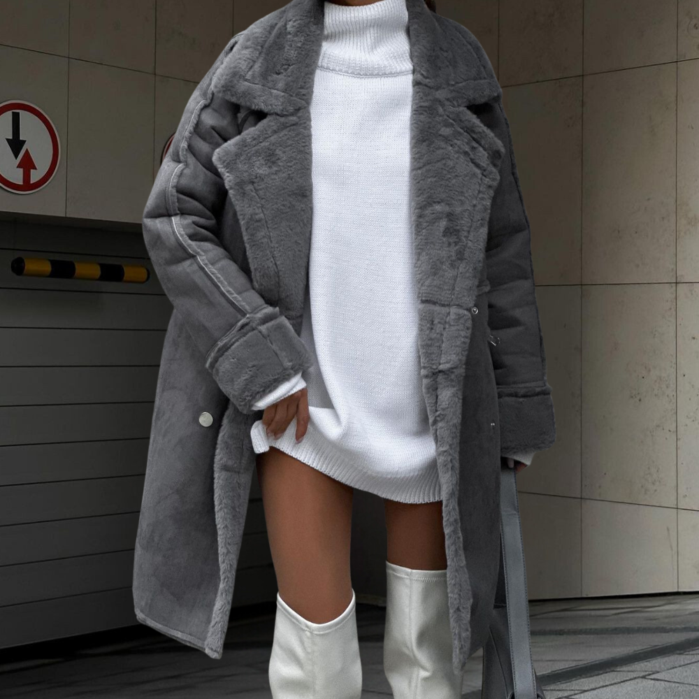 Grijze faux fur jas voor dames, gecombineerd met witte trui en hoge laarzen. Stijlvolle wintermode, trendy en warm. Perfect voor koude dagen.