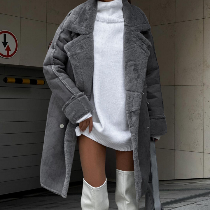 Grijze faux fur jas voor dames, gecombineerd met witte trui en hoge laarzen. Stijlvolle wintermode, trendy en warm. Perfect voor koude dagen.