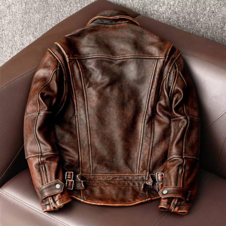 Bruine leren jas op bruine bank, vintage stijl, met stiksels en gespen. Perfect voor herenkleding, modieuze leren jassen, herfstmode.