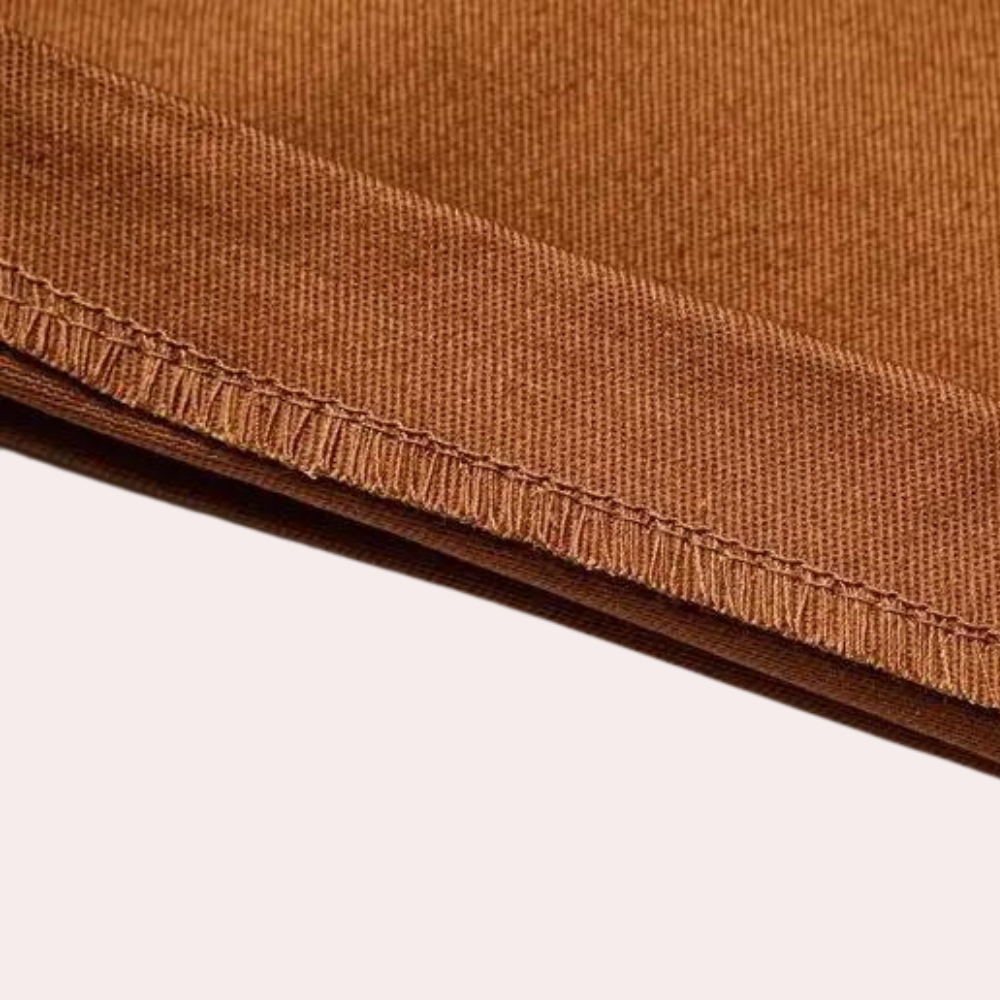 Bruine katoenen stof close-up met zichtbare stiksels, ideaal voor kleding en interieur. Hoogwaardige textielmaterialen, duurzaam en stijlvol.