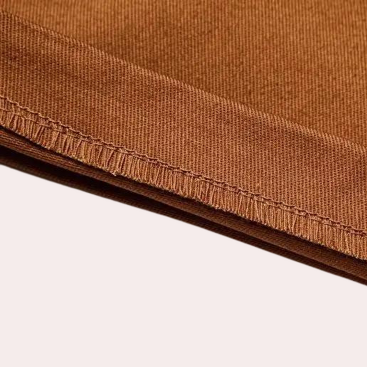Bruine katoenen stof close-up met zichtbare stiksels, ideaal voor kleding en interieur. Hoogwaardige textielmaterialen, duurzaam en stijlvol.