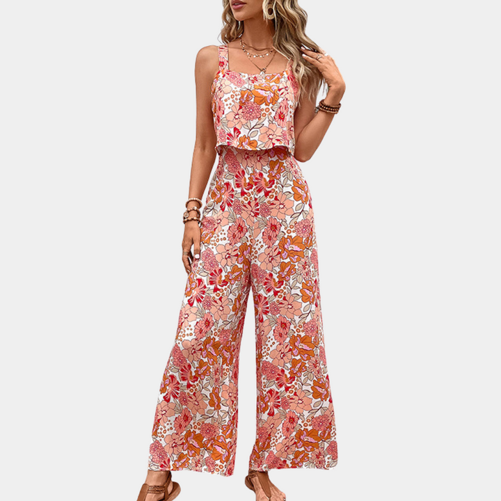 Vrouw in kleurrijke, bloemenprint jumpsuit met wijde pijpen en spaghetti bandjes, ideaal voor zomermode. Trendy dameskleding, casual stijl.