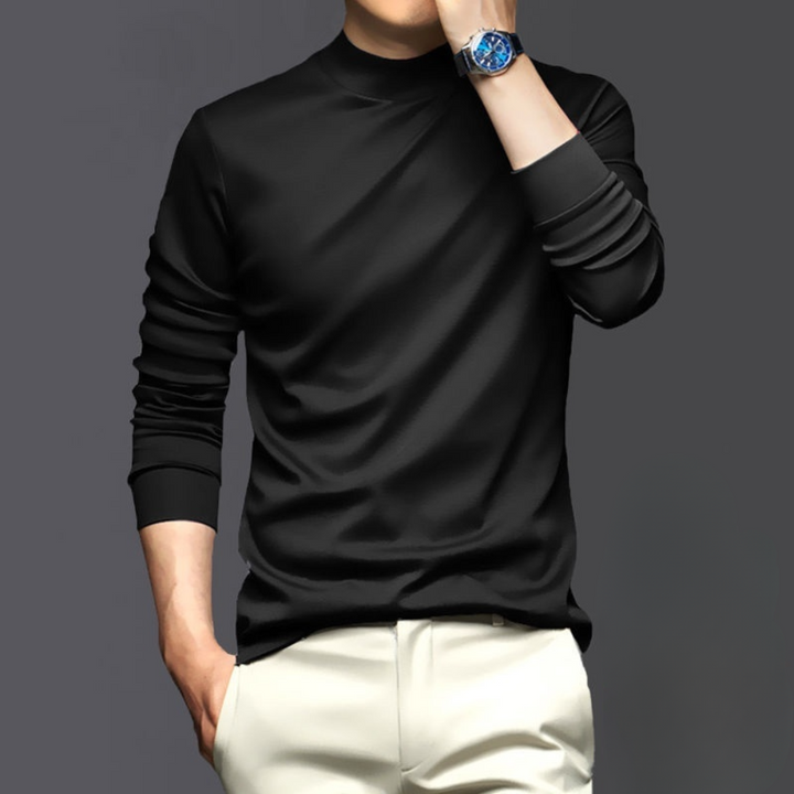 Zwarte herentrui met lange mouwen, gedragen door model met blauwe horloge, op grijze achtergrond. Stijlvolle en moderne herenkleding.