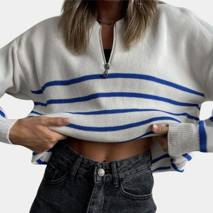 Witte trui met blauwe strepen, halve rits en lange mouwen, gedragen door persoon met zwarte jeans. Trendy damesmode, casual stijl.