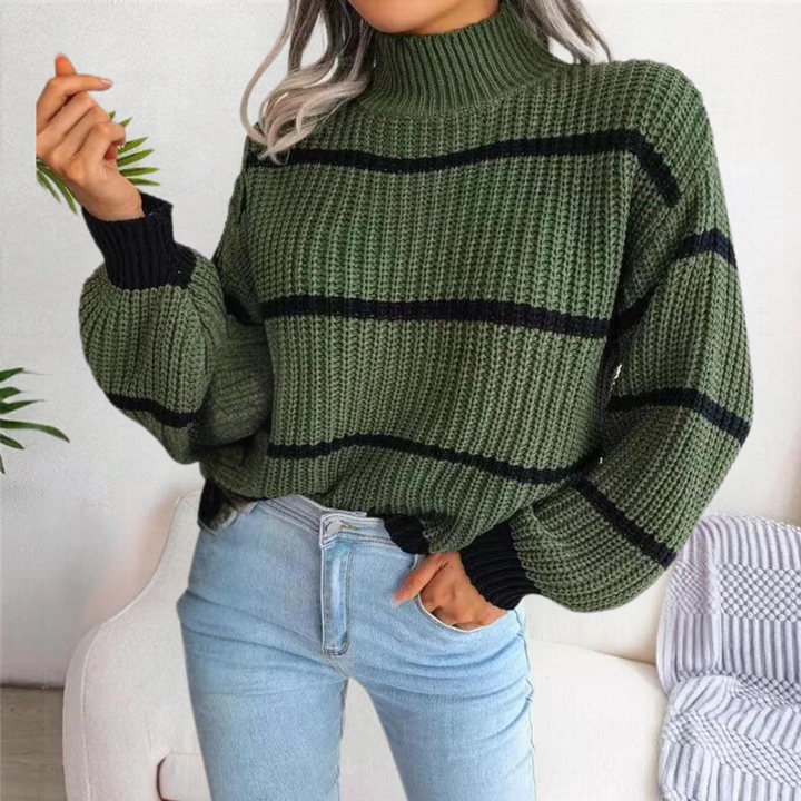 Vrouw draagt groene gebreide trui met zwarte strepen, gecombineerd met lichtblauwe jeans. Modieuze herfstoutfit, casual dameskleding.