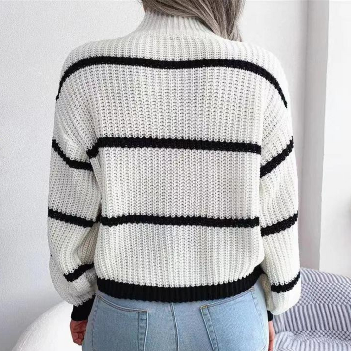 Witte gebreide trui met zwarte strepen, gedragen door persoon met lang haar, gecombineerd met blauwe jeans. Stijlvolle damesmode, casual outfit.