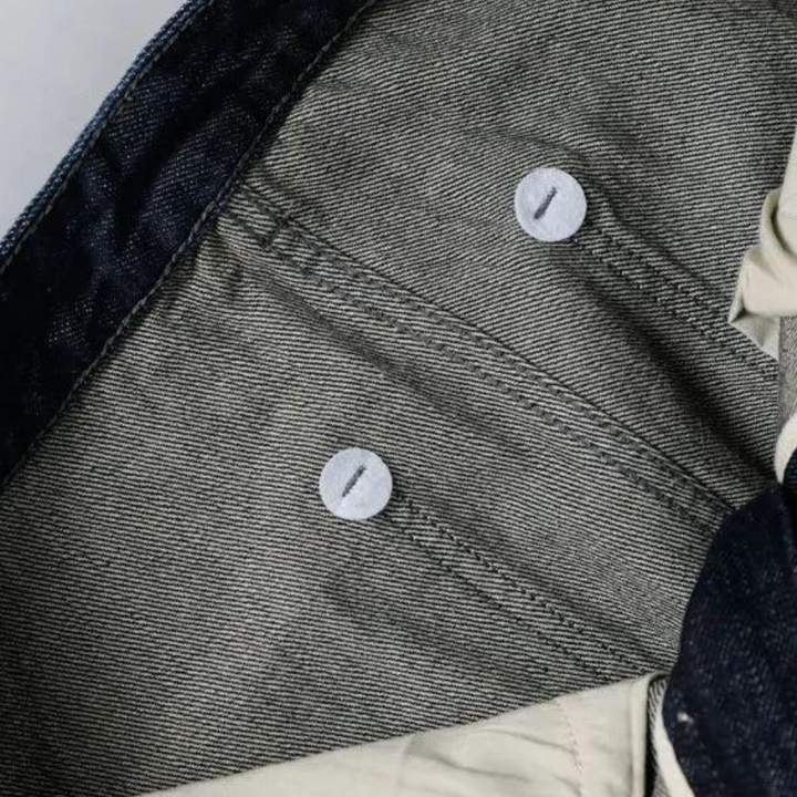 Grijze denim binnenkant van een jas met zichtbare stiksels en knopen. Hoogwaardige spijkerstof, detailopname, modeaccessoire.