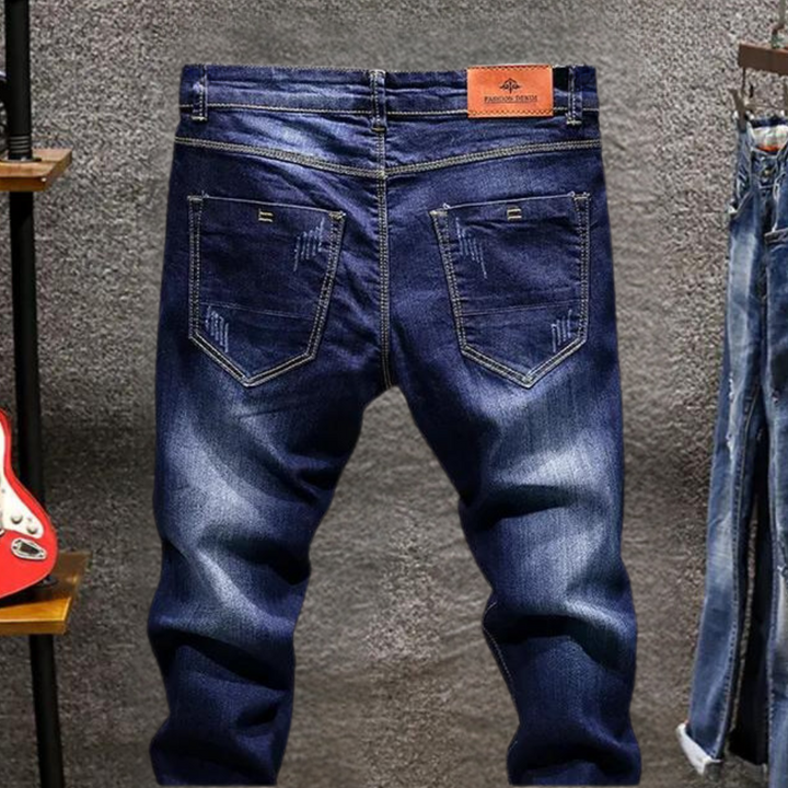 Donkerblauwe spijkerbroek met vintage wassing en leren label, herenmode, casual denim, trendy jeans, achteraanzicht, detail zakken.