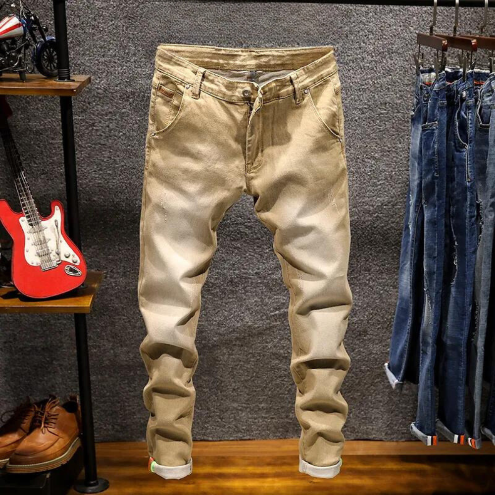 Khaki herenjeans opgehangen in een kledingwinkel, omgeven door een gitaar en andere spijkerbroeken. Modieuze casual broek, perfect voor dagelijks gebruik.