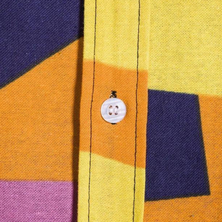 Geel en paars geometrisch patroon op katoenen overhemd met witte knoop. Modern design, kleurrijke mode, hoogwaardige stof.