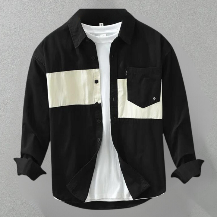 Zwart overhemd met witte horizontale streep en borstzak, gedragen over een wit T-shirt. Modieuze herenkleding, casual stijl.