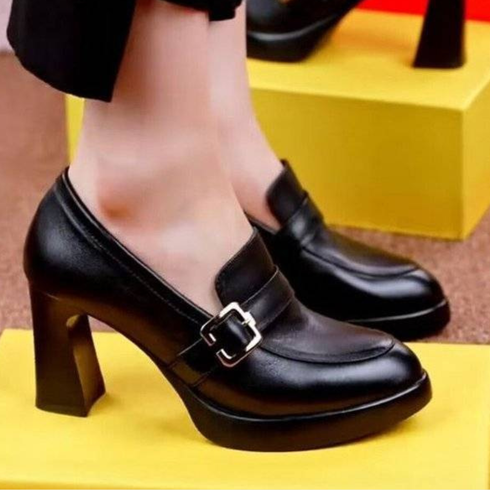 Zwarte leren damesschoenen met hoge hak en gesp, stijlvolle pumps op gele achtergrond. Perfect voor modebewuste vrouwen.