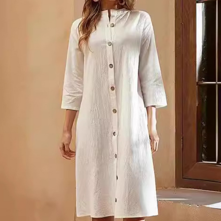 Witte linnen jurk met knoopsluiting, driekwart mouwen en een elegante, minimalistische stijl. Perfect voor zomerse casual en formele gelegenheden.