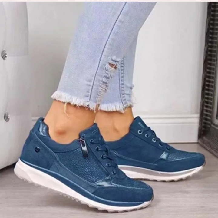 Donkerblauwe dames sneakers met witte zool, gedragen met lichtblauwe gescheurde jeans. Comfortabele, modieuze schoenen voor dagelijks gebruik.