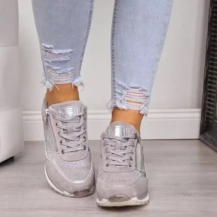 Zilveren sneakers met glinsterende details, gedragen met lichtblauwe gescheurde jeans. Modieuze dames schoenen, casual stijl, trendy look.