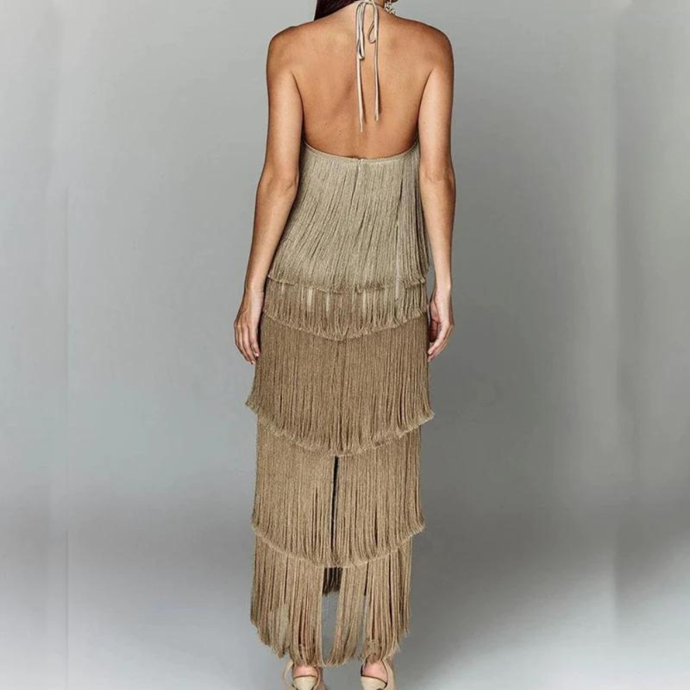 Vrouw in elegante, beige-franjejurk met open rug, perfect voor avondkleding. Trendy mode, stijlvolle jurk, dameskleding, chique uitstraling.