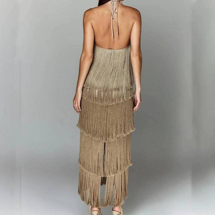 Vrouw in elegante, beige-franjejurk met open rug, perfect voor avondkleding. Trendy mode, stijlvolle jurk, dameskleding, chique uitstraling.