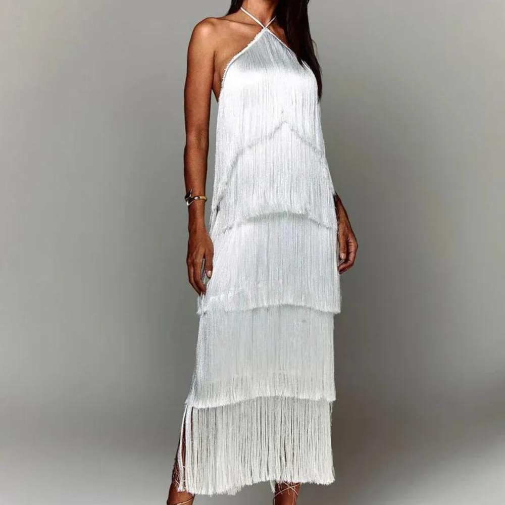 Witte franjesjurk met halternek, elegante lagen en vloeiende textuur. Perfect voor zomerse evenementen en stijlvolle gelegenheden.