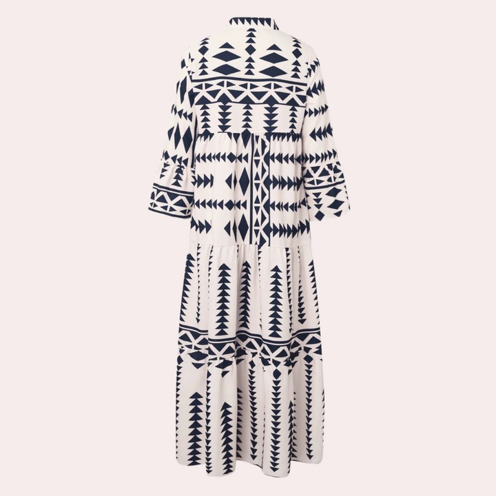 Achterkant van een lange, witte jurk met geometrische zwarte patronen, driekwart mouwen en een losse pasvorm. Perfect voor zomer- en boho-stijl.