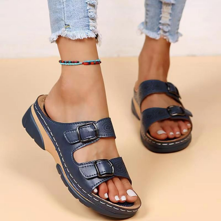 Donkerblauwe dames sandalen met dubbele gespen, comfortabele sleehak, gedragen met gescheurde jeans. Perfect voor zomerse casual outfits.