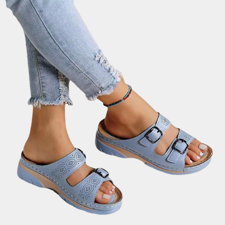 Lichtblauwe dames sandalen met dubbele gespsluiting en geperforeerd ontwerp, gedragen met gerafelde jeans. Comfortabele zomerschoenen.