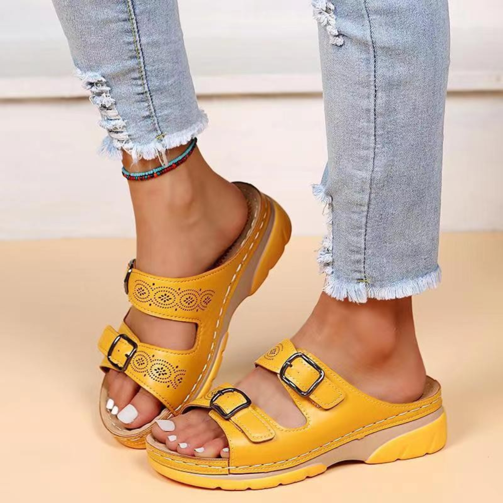 Gele dames sandalen met dubbele gespen en comfortabele zool, gedragen met lichtblauwe gescheurde jeans. Perfect voor zomerse casual outfits.