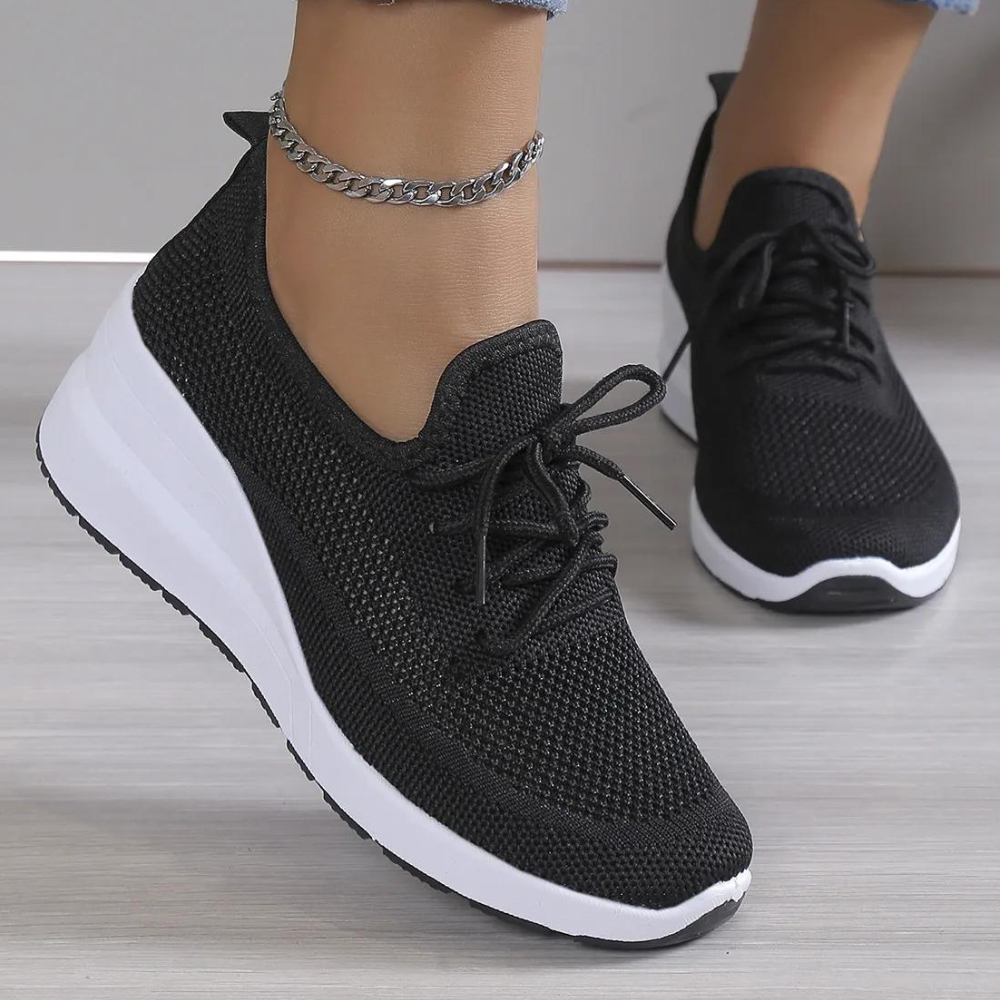 Zwarte dames sneaker met witte zool, gebreid bovenwerk en veters. Comfortabele sportschoen voor dagelijks gebruik. Trendy en stijlvol design.