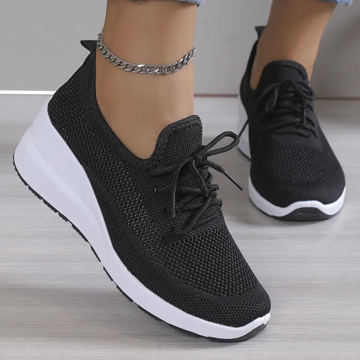Zwarte dames sneaker met witte zool, gebreid bovenwerk en veters. Comfortabele sportschoen voor dagelijks gebruik. Trendy en stijlvol design.