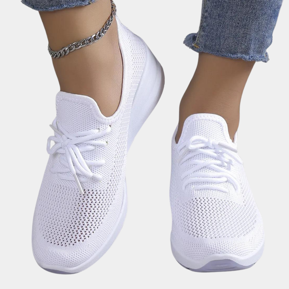 Witte dames sneakers met ademend mesh, comfortabele pasvorm en vetersluiting, gedragen met jeans. Perfect voor casual en sportieve outfits.