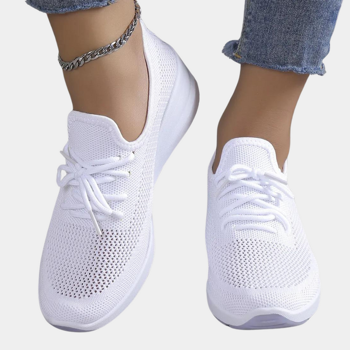 Witte dames sneakers met ademend mesh, comfortabele pasvorm en vetersluiting, gedragen met jeans. Perfect voor casual en sportieve outfits.