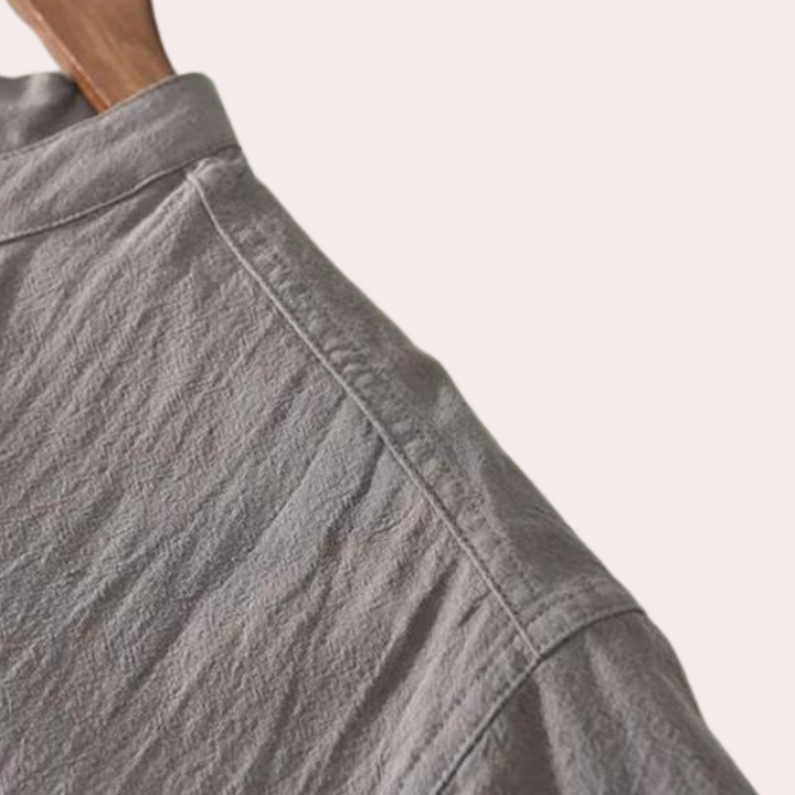 Grijze linnen blouse met gedetailleerde textuur, zichtbaar stiksel en kraag. Hoogwaardige stof, ideaal voor casual en formele gelegenheden.