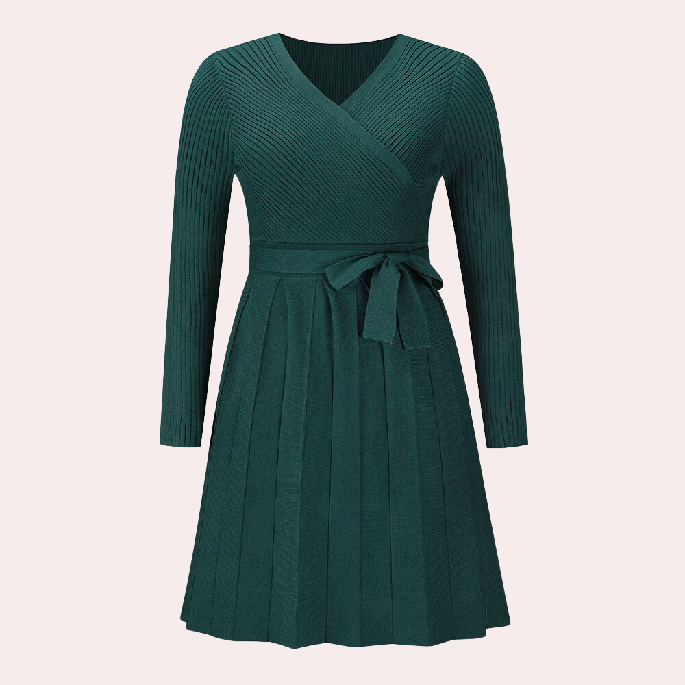 Donkergroene gebreide jurk met lange mouwen en V-hals, voorzien van een strikceintuur en geplooide rok. Perfect voor herfstmode en casual chic looks.