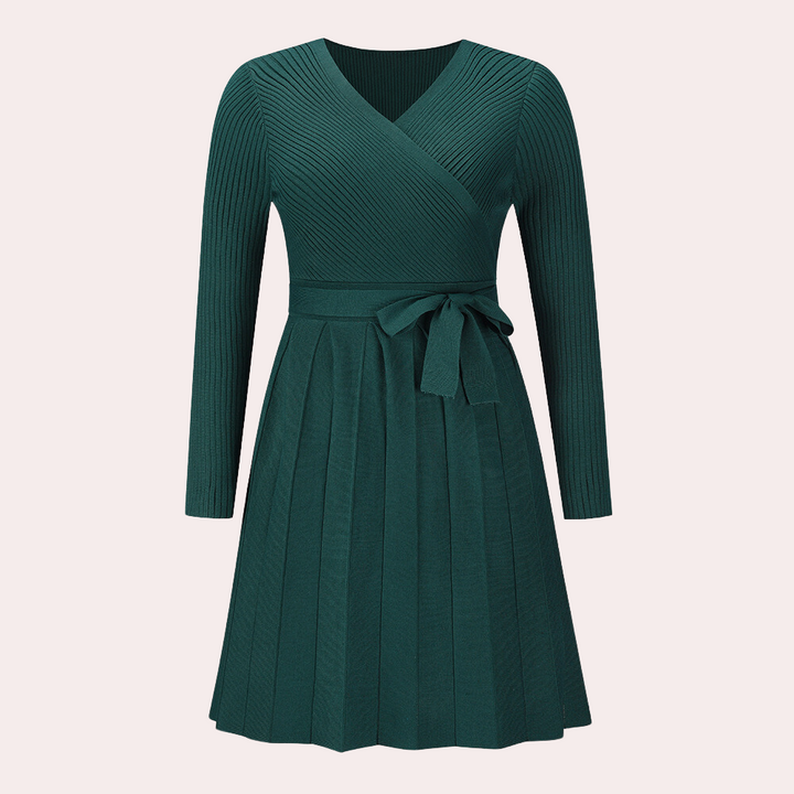 Donkergroene gebreide jurk met lange mouwen en V-hals, voorzien van een strikceintuur en geplooide rok. Perfect voor herfstmode en casual chic looks.