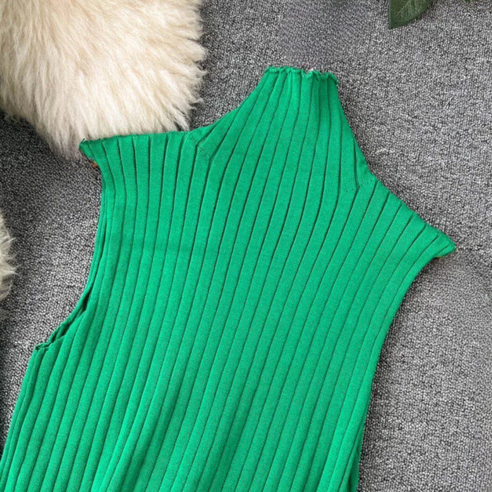 Groene geribbelde mouwloze top op grijze achtergrond, met schouderdetail. Modieuze dameskleding, trendy zomeroutfit, casual stijl.