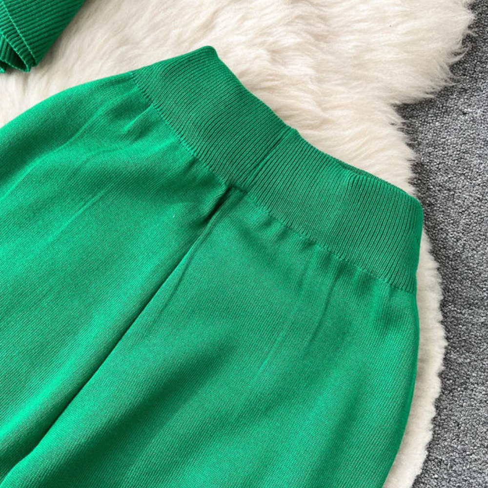 Groene joggingbroek met elastische tailleband, zachte stof, op een witte schapenvacht en grijze vloer. Comfortabele damesmode, casual stijl.