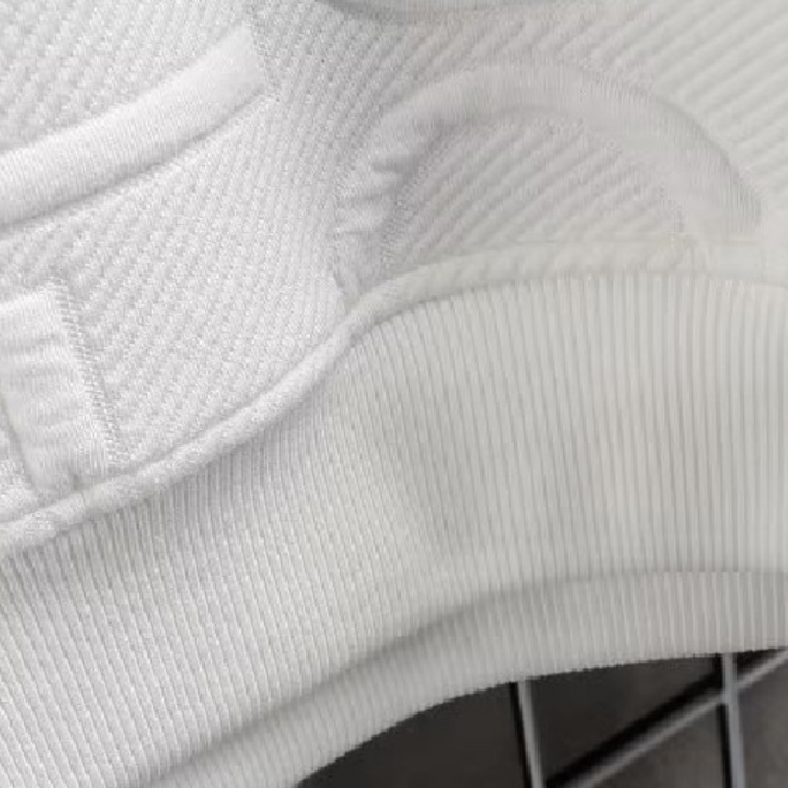 Witte gebreide trui detail met ribbelpatroon en zak, close-up textuur. Hoogwaardige katoenen stof, modieuze kleding, comfortabele pasvorm.