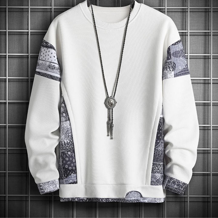 Witte trui met zwart-witte paisley-patronen en lange ketting, moderne herenkleding, stijlvolle streetwear, casual mode, trendy design.
